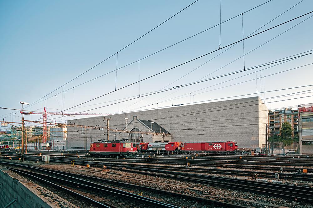 Zum Gleisbett im Süden zeigt sich das MCBA als fast fensterloser Monolith. Nur ein kleiner Rest des alten Lokschuppens erinnert an die Geschichte des Areals.