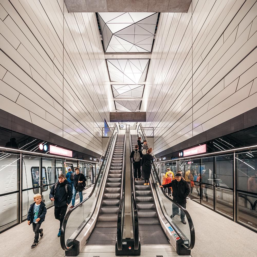 Die Station Gammel Strand liegt teilweise unter einem Kanal. Daher gibt es keine Oberlichter und keine zentrale Treppenanlage nach außen. Die Rolltreppen führen seitlich versetzt nach oben.