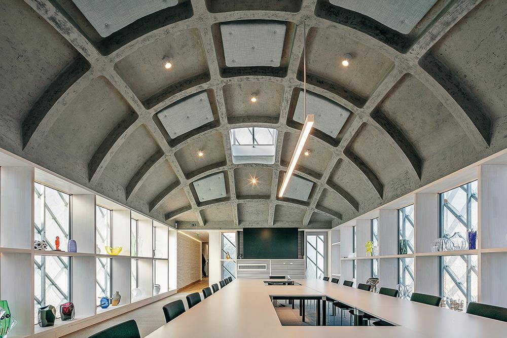 Über die gewölbte Betonrippendecke im Obergeschoss spannt sich ein Kaltdach mit Glasschindeldeckung.