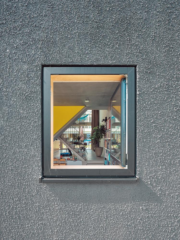 Leicht verschobene Fensterachsen geben der schwarz verputzten Nordfassade formale Spannung. Die Fensterrahmen ordnen sich farblich unter.