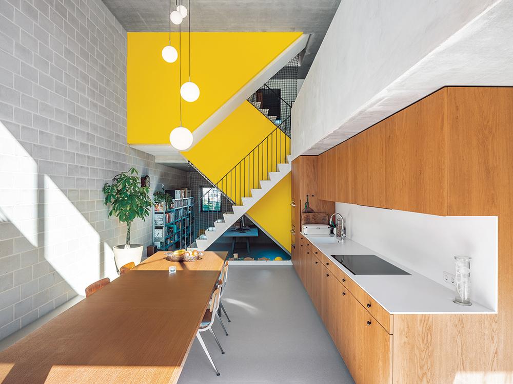 Each of the two dwelling units has its own staircase in the centre of the house. Between them, bright yellow walls act as visual, sound and fire barriers.