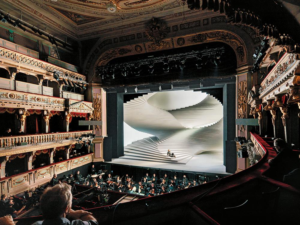The minimalist stage design contrasts strongly with the auditorium’s lavish decor.