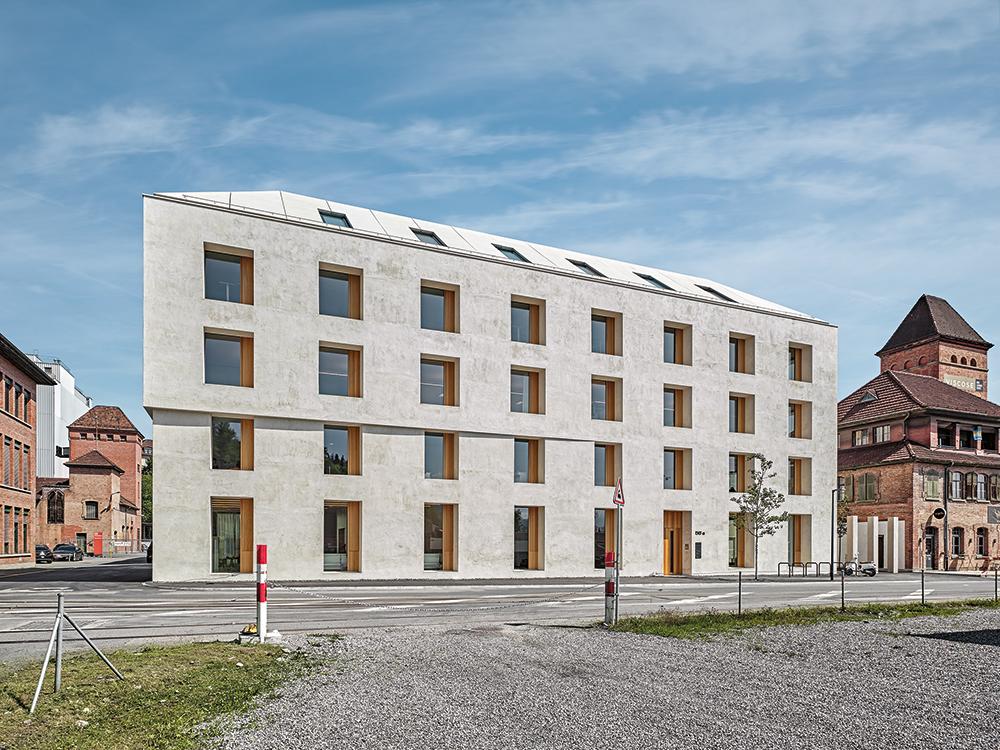Das Büro- und Schulungsgebäude von Baumschlager Eberle Architekten in Emmenweid entstand auf einem ehemaligen Industrieareal. Um die Speichermasse zu maximieren, besteht sein Walmdach aus Beton.