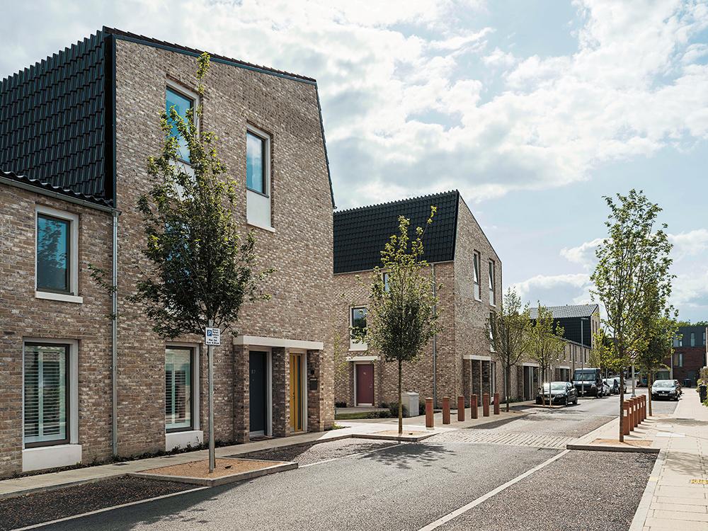 The individual rows of houses are only 14 m apart. High wooden fences separate the private gardens from the public pathways running between them.