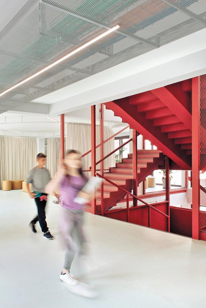 Mit Vorhängen lassen sich informelle Lernbereiche von den offenen Erschließungszonen abgrenzen. Die Treppe ist analog zu den Laubengängen vor den Klassenzimmern aus Stahl.