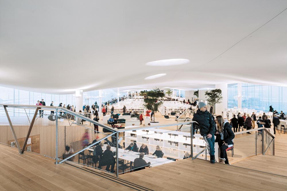 Das Dachgeschoss nimmt einen fließenden Gemeinschaftsraum zum Lesen und Streamen auf. Durchgängige Glasfassaden geben den Panoramablick über die Stadt frei.