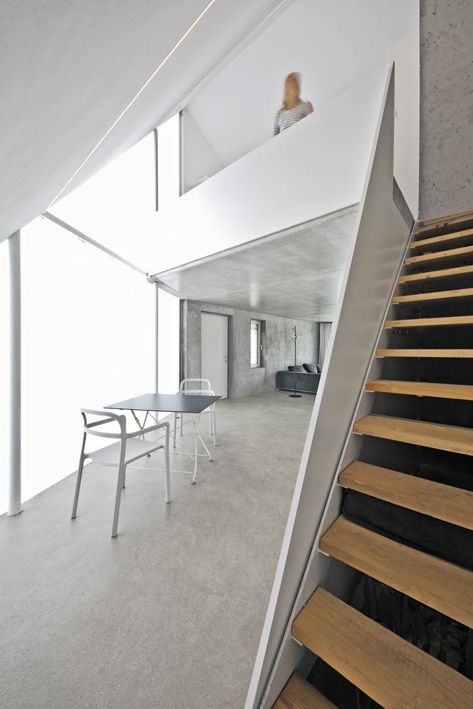 Eine platzsparende, steile Stahltreppe führt ins Obergeschoss. Der Schlafbereich auf der Galerie ist zum Koch-, Essund Wohnbereich im Erdgeschoss offen.
