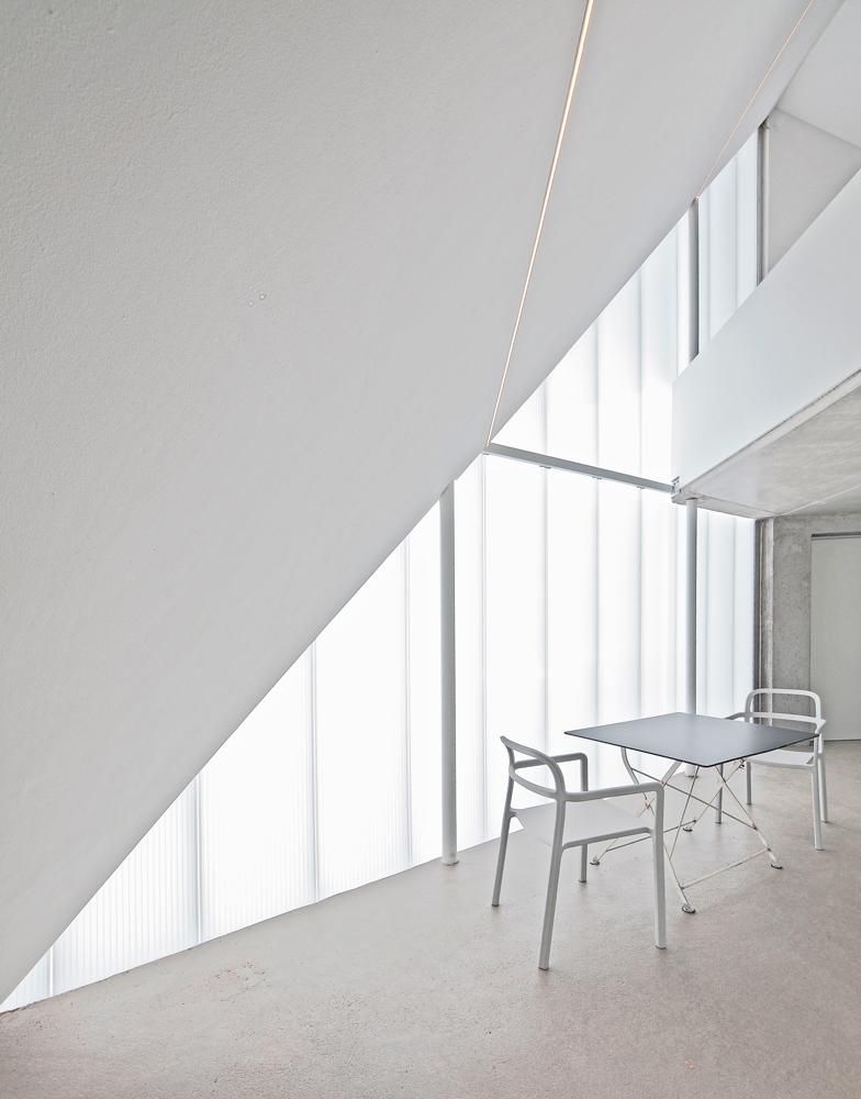 Der zweigeschossige Bereich zur Straße wird durch eine transluzente Polycarbonatfassade belichtet. Sie schützt vor Einblicken und filtert den Ausblick auf die banale Umgebung.