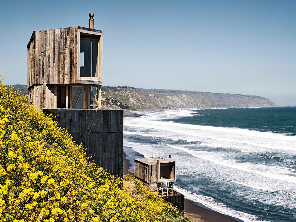 Erected on tall wooden bases, La Loica and La Tagua stand on the 80-m-high Pacific coast in Matanzas. Their weathered envelope is made from reused railway sleepers.
