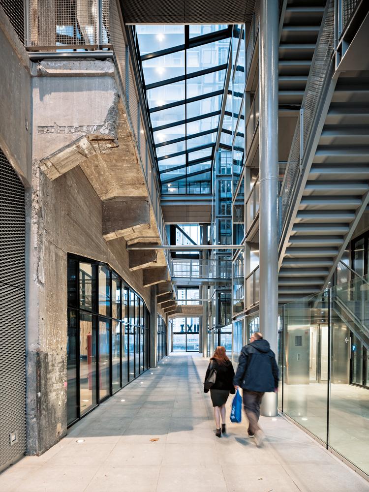 Die öffentliche Passage verbindet den Hafenkai mit dem angrenzenden Wohngebiet. Durch ihre Fenster fällt der Blick in die Trainingshalle. Oberhalb des Glasdachs sind die Laubengänge der Wohnungen zu erkennen.
