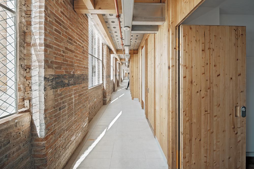 The precast concrete access gallery units are pierced by glass blocks and set on laminated timbers without imposing loads on the existing structures.