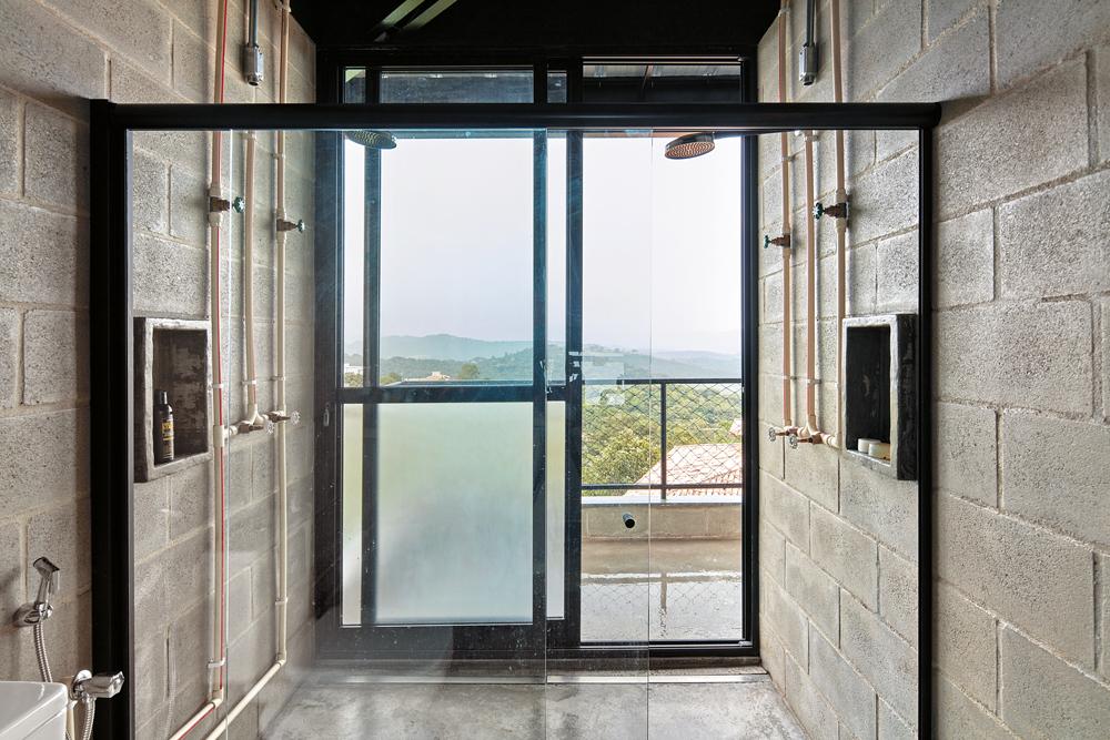 Im Badezimmer wie auch im gesamten Wohnhaus sorgen roh belassene Materialien und offen geführte Installationsleitungen für eine industrielle Anmutung.