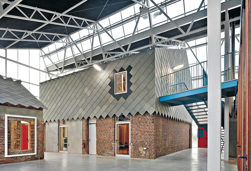 Die Halle dient als thermischer Pufferraum, nur die „Häuser im Haus” sind teilweise beheizt. Hinter den Faserzementschindeln verbirgt sich daher eine Dämmschicht.