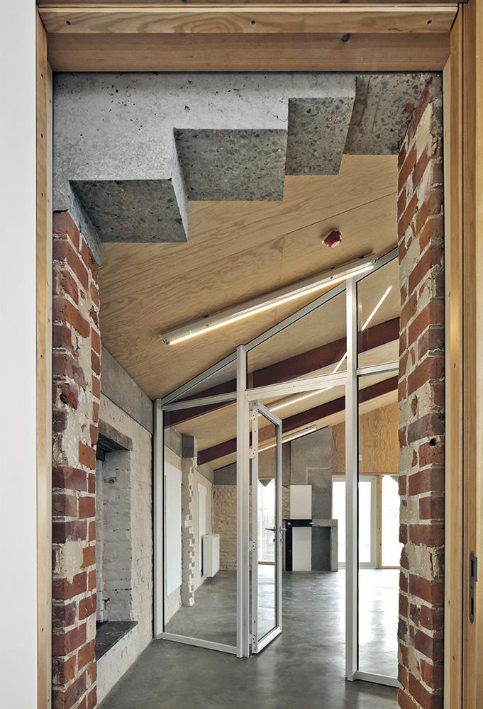 Die Halle dient als thermischer Pufferraum, nur die „Häuser im Haus” sind teilweise beheizt. Hinter den Faserzementschindeln verbirgt sich daher eine Dämmschicht.
