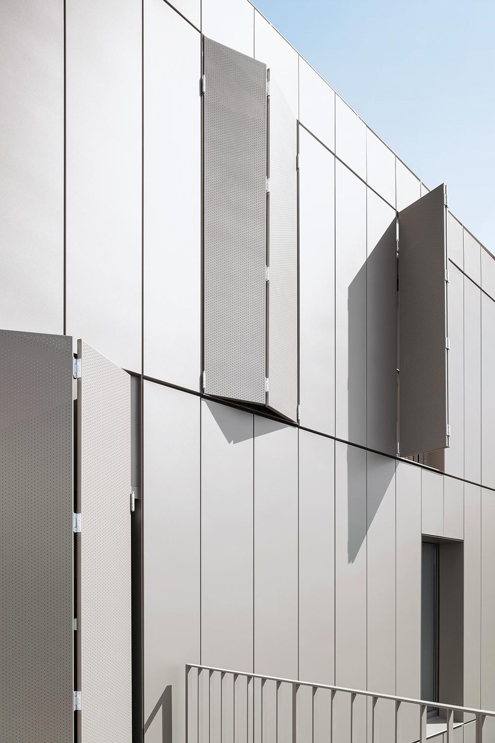 Die Südwestfassade zum Innenhof ist mit Aluminiumpaneelen verkleidet. Für Sicht- und Sonnenschutz sorgen Faltschiebeläden.