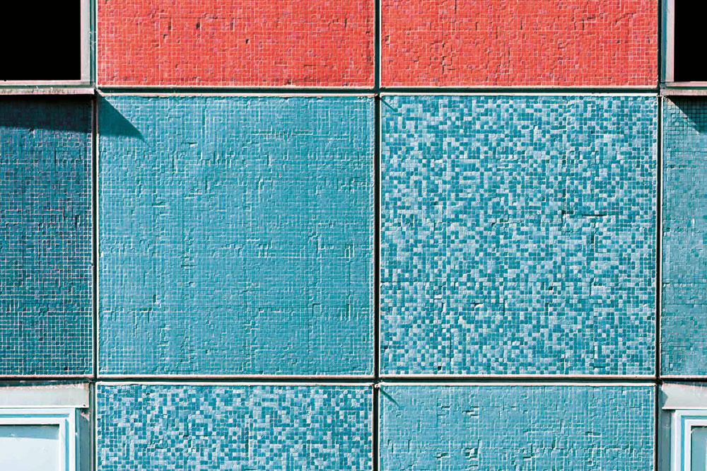 Orange und türkise Mosaikfliesen auf Betonfertigteilen prägten die Fassade des Bestandsbaus. Sie wurde abgetragen und durch eine verglaste Elementfassade ersetzt.