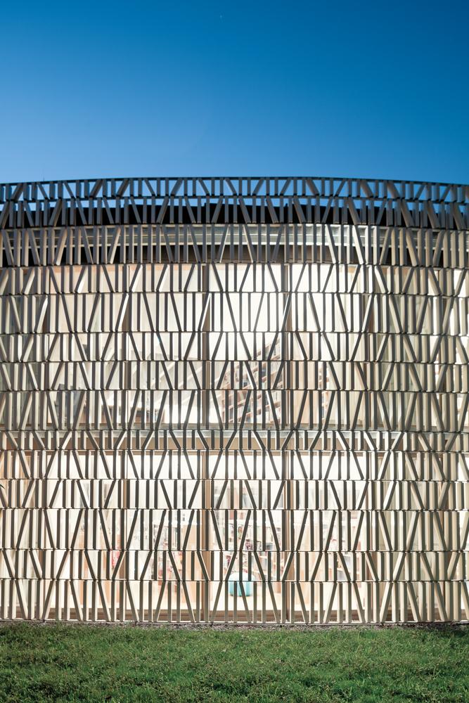 Nachts dringt warmes Licht durch die äußere Hülle aus Keramikelementen. Die Fassade erweckt Assoziationen zu Büchern oder auch zu Schriftzeichen und Zahlen.