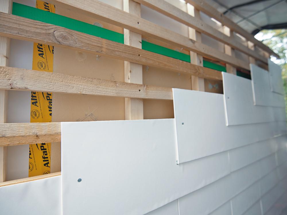 Eine vorgehängte, hinterlüftete Fassade aus Getränkekarton schützt die Tragkonstruktion.
