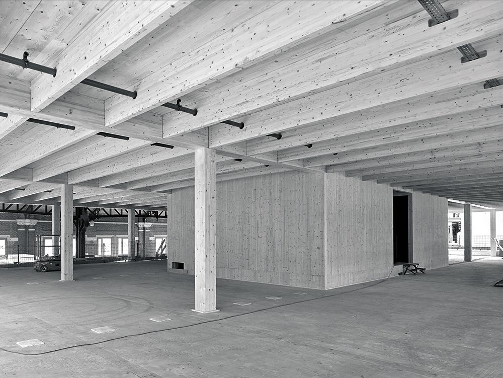 Dort, wo Büroflächen unter den Holzuntersichten des Hallendachs liegen, sind Konvektoren zwischen Holzrippen auf der Bodenplatte integriert.