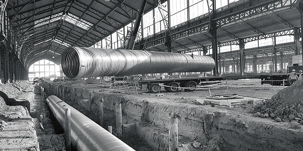 Die PV-Anlage auf den Dachflächen verwandelt den ehemaligen Güterbahnhof in eine Solarfabrik. Das Regenwasser wird in röhrenartigen Tanks im Boden der zentralen Halle gesammelt.
