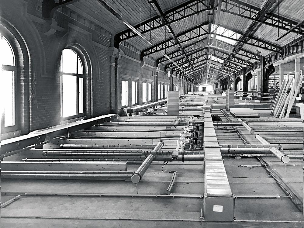 Dort, wo Büroflächen unter den Holzuntersichten des Hallendachs liegen, sind Konvektoren zwischen Holzrippen auf der Bodenplatte integriert.