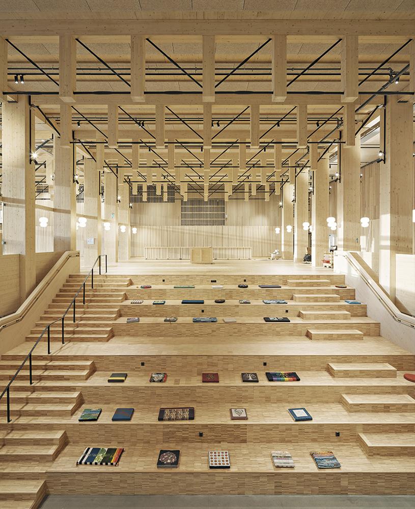 Eine offen liegende Deckenkonstruktion aus Holz und Stahl prägt den Charakter des Hauptfoyers. Sitzstufen verleihen dem Raum den Charakter eines Marktplatzes.