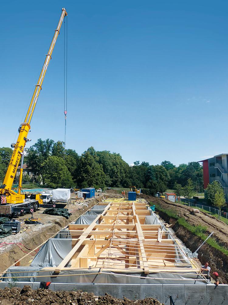 Das Gebäude aus vorgefertigten Modulen lagert auf Holzpfählen, dazwischen verläuft eine Techniktrasse.