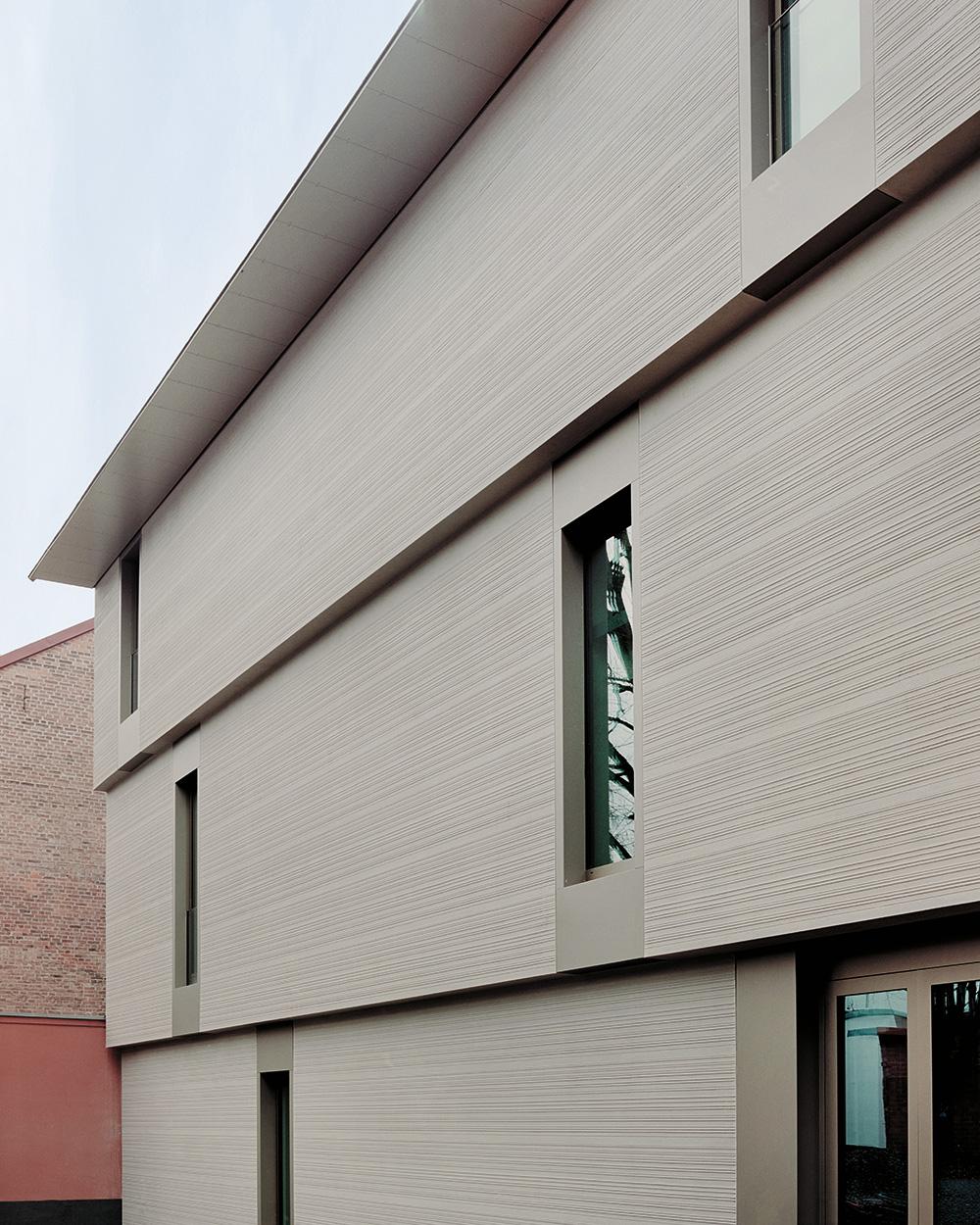 Die Geschossdecken kragen in jedem Stockwerk weiter aus. Der gerillte Putz kontrastiert mit den glatten Aluminiumrahmen der bodentiefen Fensteröffnungen.