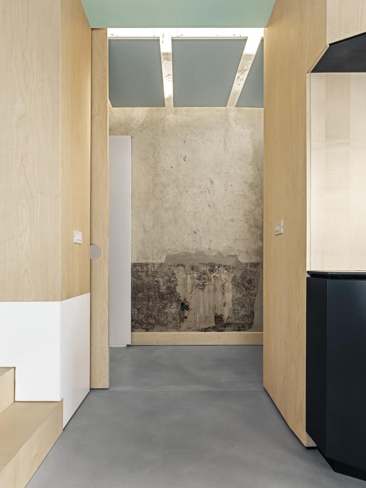 Maple veneer and render without painted finish, steel beams and cement screed floors: the living room displays the entire colour palette and diversity of selected materials of the interior design.