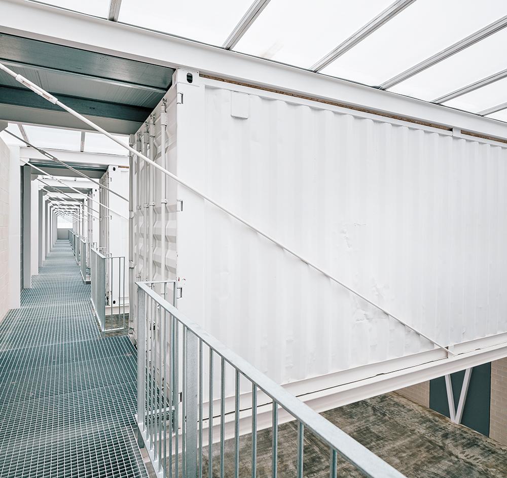 Die früheren Schiffscontainer wurden vom Rost befreit und mit einer weißen Brandschutzbeschichtung gestrichen. Jetzt dienen sie als immobiles Warenlager.