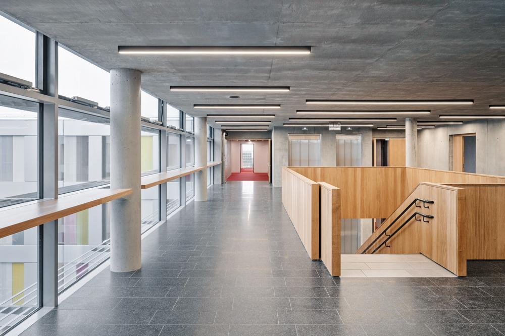 Der mittlere Gebäudeteil aus Beton verbindet die beiden Bürotrakte miteinander und nimmt die Erschließung auf. Den Mittelpunkt bildet das offene Treppenhaus.