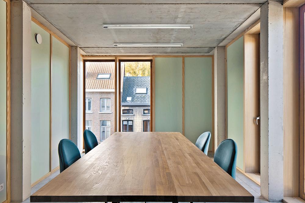 Auch im Inneren tritt die Aufteilung der Fassade in Erscheinung. Die geschlossenen Wandelemente sind mit hellgrün gestrichenen Sperrholzplatten verkleidet.
