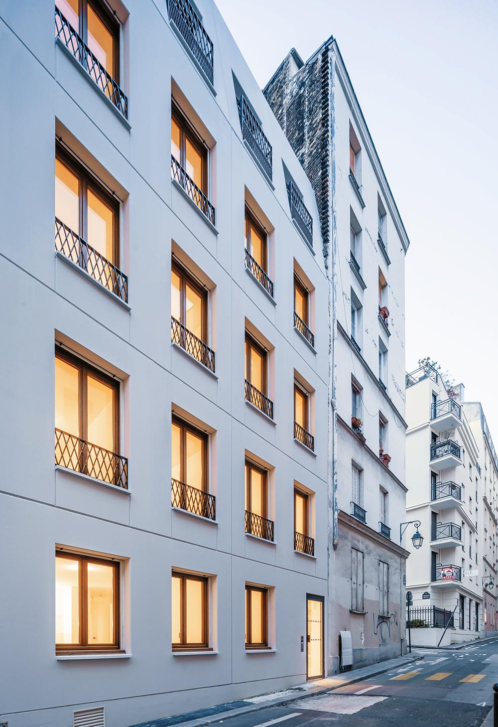 Die Lochfassade an der Rue Sibuet ist mit raumhohen Betonfertigteilen verkleidet. Hier verzieren schmale Geländer mit gekreuzten Stäben die nüchternen Flächen.