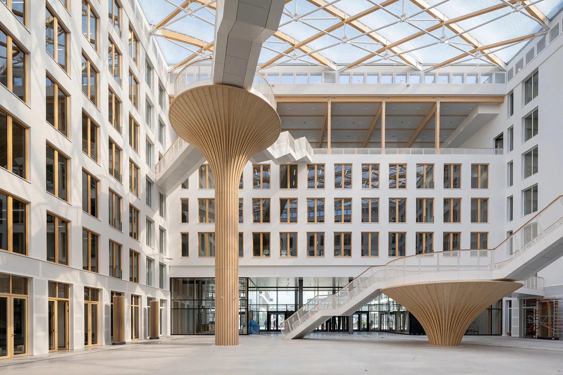 Das Carré umschließt einen Innenhof, der mit seinen der Natur nachempfundenen Stützen und einer luftigen Überdachung aus Folienkissen identitätsstiftend gestaltet ist.