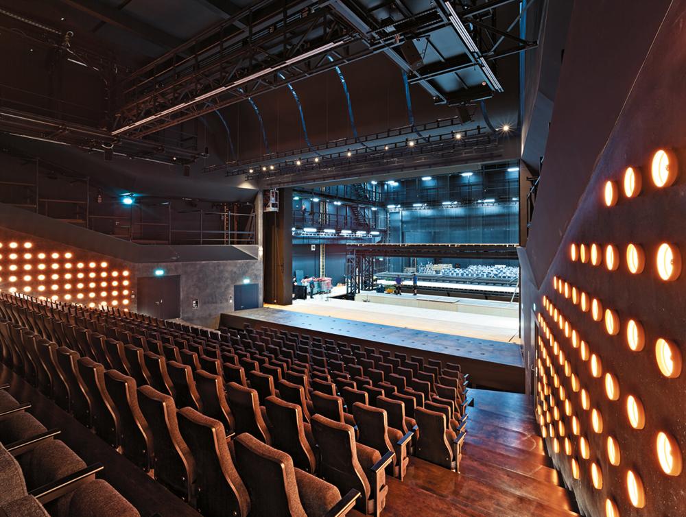 Im großen Theatersaal ist die Bühne so nah es ging an die Zuschauertribüne gerückt. In Tontöpfe eingelassene LEDs werfen warmes Licht in den Raum.
