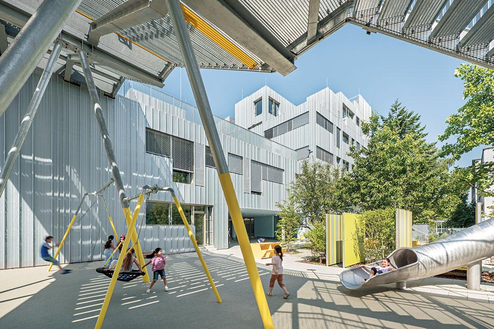 Großzügige Freibereiche unterstützen die Bewegungsfreude. Die Treppen sind so gestaltet, dass die Kinder sie gerne nutzen, ebenso wie die Außentreppen mit Röhrenrutschen.
