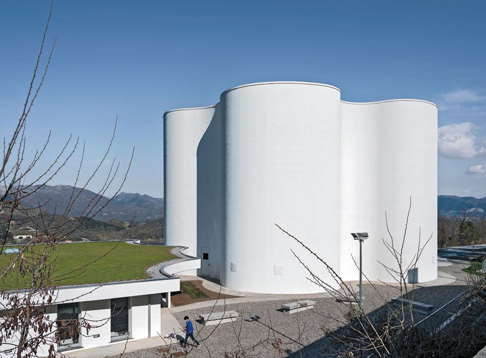 Das flache Gemeindezentrum stammt auch aus der Feder Mario Cucinellas. Der strenge Baukörper nimmt mit seinem organischen Dachrand Bezug zur Kirche.