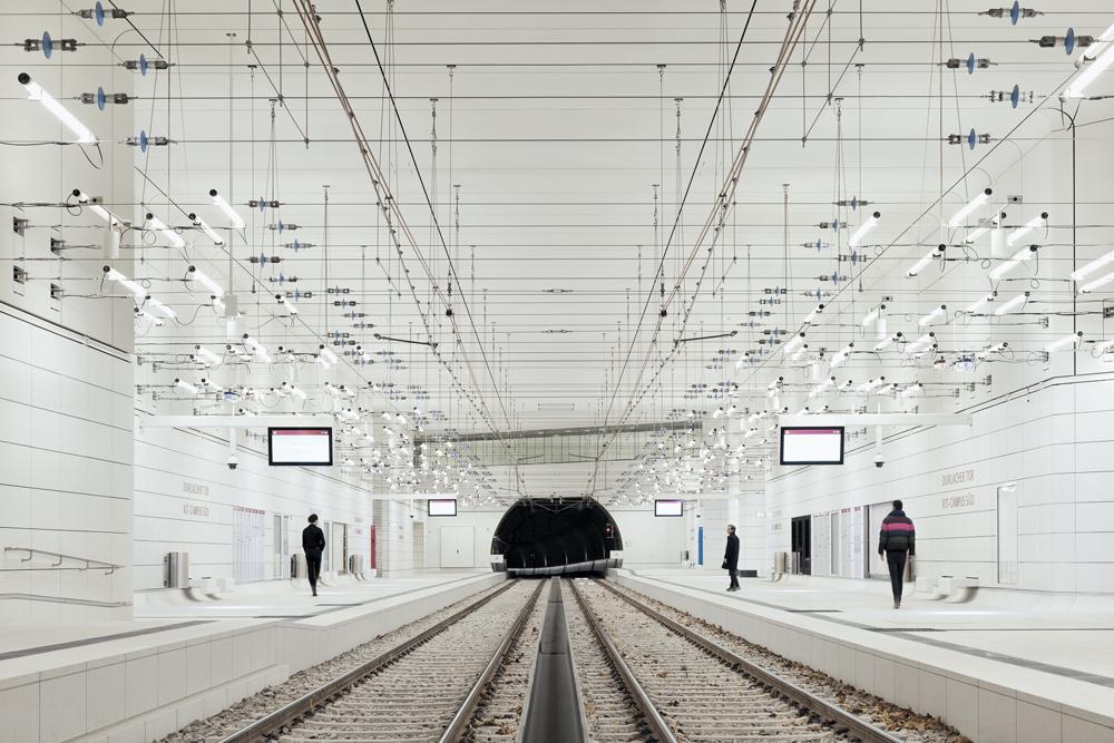 Optisch werden die Seile für die Beleuchtung eins mit der Oberleitung der Straßenbahn. Sie sind jedoch konstruktiv und elektrisch strikt getrennt. Dort wo sie die Oberleitungen aus Kupfer queren, sind Isolatoren eingebaut (im Foto gut zu sehen), um jeglichen Stromüberschlag auszuschließen.