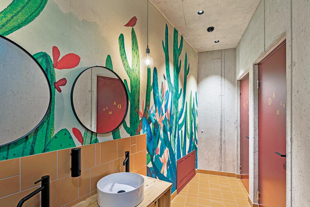 Großformatige Wandgemälde mit Pflanzenmotiven sorgen für einen naturnahen Spirit in den fensterlosen Sanitärbereichen.