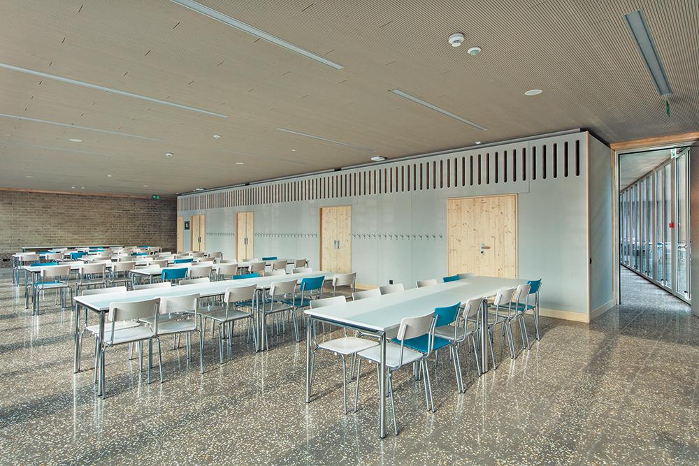 Dark grey terrazzo with yellow aggregate and built-in fir elements with light grey painted finish define the appearance of the two cafeteria spaces.