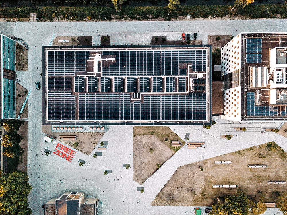 Auf dem Flachdach und den mittigen Sheds befinden sich 1200 PV-Paneele. Die Sheds versorgen den Mittelflur im obersten Geschoss und das Foyer mit Tageslicht.