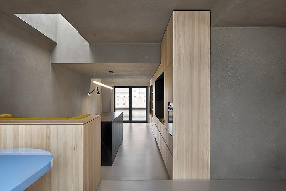 A two-storey airspace connects the living area and the roof terrace. A large-format window provides indirect lighting.