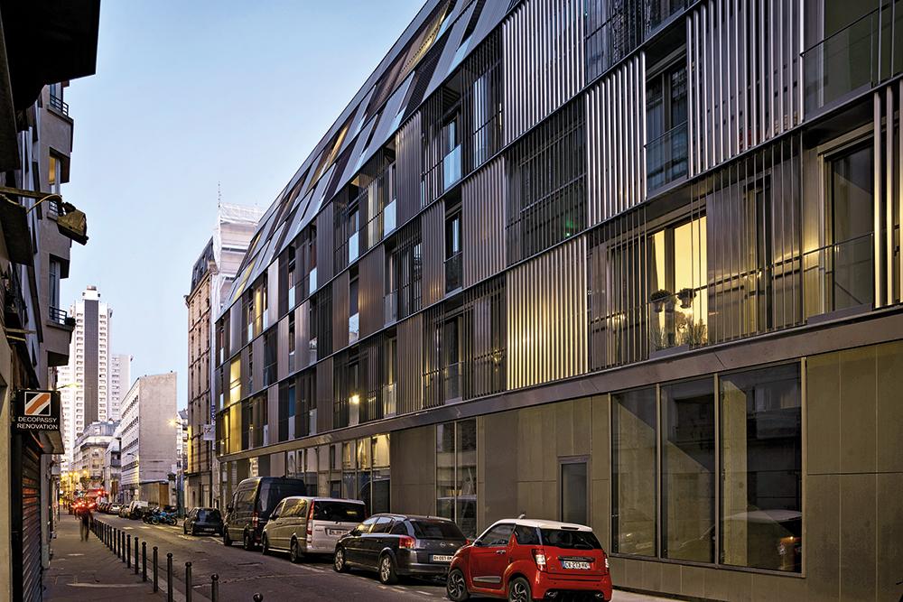 Feststehende Lamellen aus Aluminium bilden eine zweite Hülle vor der Fassade und schützen die durchlaufende Balkonzone vor Einblicken.