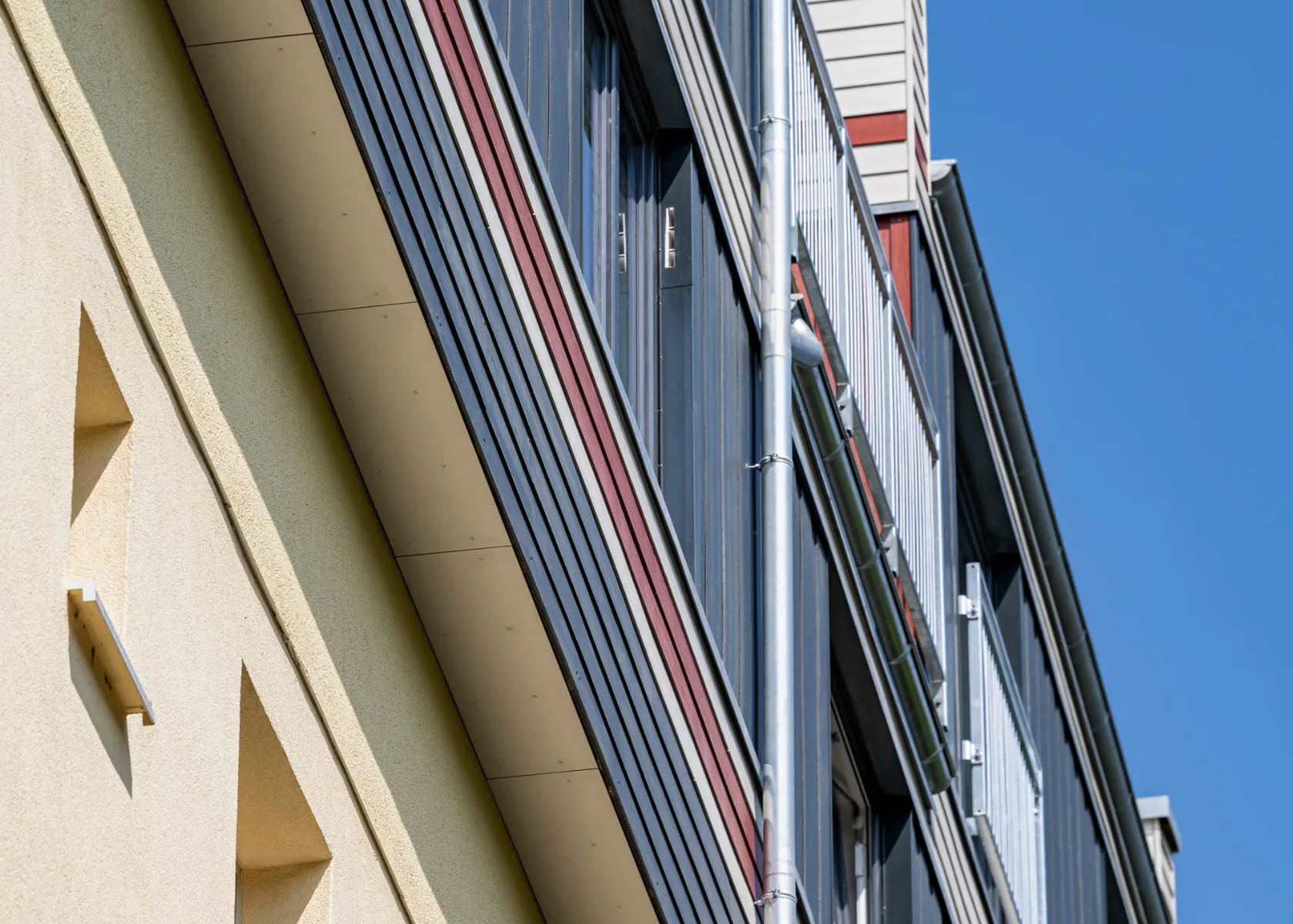Die Kombination von horizontal und vertikal angeordneten Hardie-Plank-Elementen sowie die dreifarbige Gestaltung prägen die Hülle der Aufstockung. Foto
