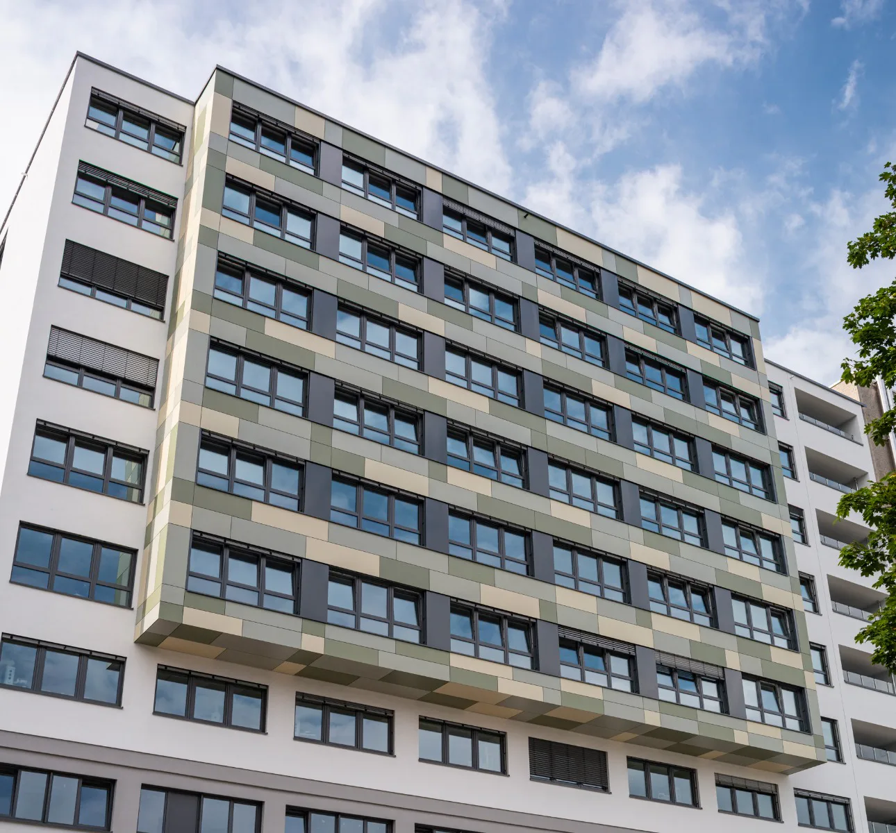 Der auskragende Bereich der Vorhangfassade ist mit Faserzementplatten farblich abgesetzt und akzentuiert die rund 40 m lange Fassade des Anbaus