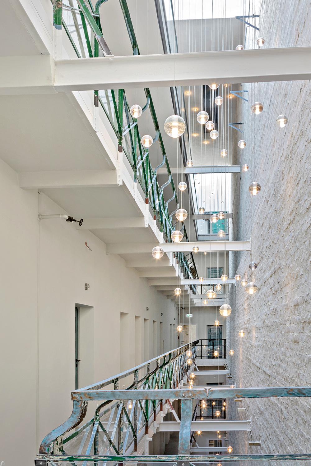 Das zentrale Atrium mit schmiedeeisener Brüstung ist das Herzstück des ehemaligen Frauengefängnisses. Es erschließt heute nicht mehr die Zellen, sondern die Hotelzimmer.