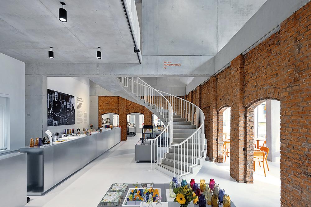Unter dem geschwungenem Dach liegt der neue Haupteingang des Kulturzentrums mit Cafeteria und Museumsshop. An einigen Stellen verweisen Ziegelmauern auf Bestandsbauten der Fabrik.
