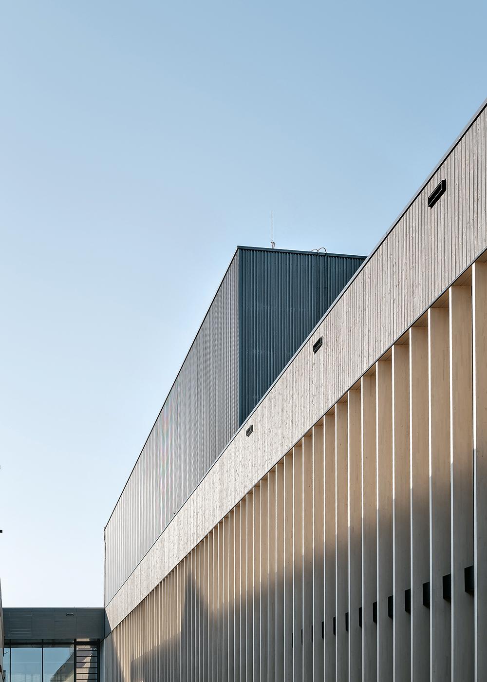 Das Audimax und die Sporthallen ragen als Kuben aus dem Flachdach heraus. Die Büroriegel auf dem Platz der alten Sporthallen sind im Bau (2. Bauabschnitt 2022–2024).