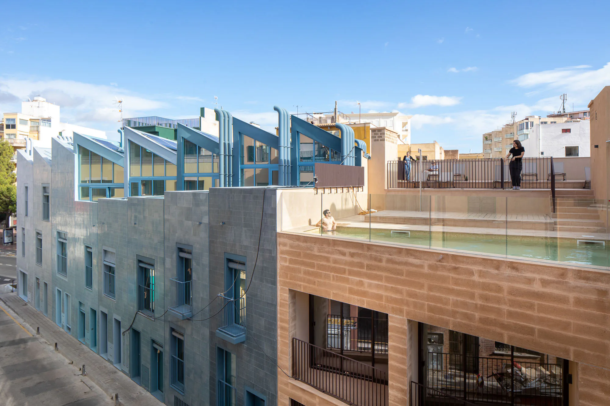 Gemeinschaftseinrichtungen wie der Swimmingpool auf der Dachterrasse des braunen Hauses stehen den Mietern aller Einheiten zur Verfügung.