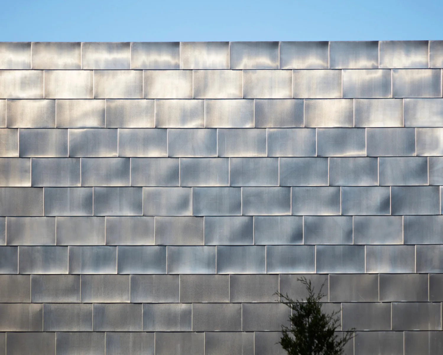 Der Neubau weist eine schiffsförmige, zinkverkleidete Fassade auf.